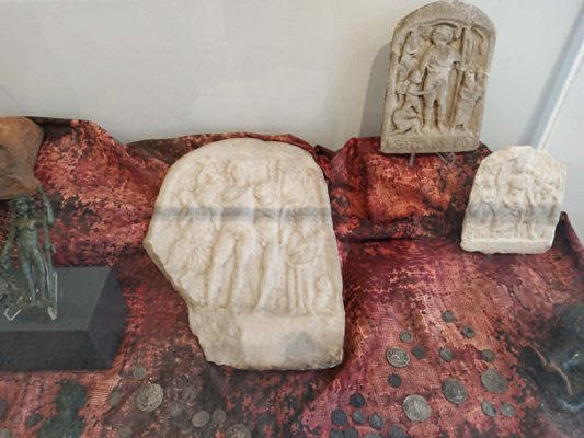 Adak plakalarından birinde Dionysos satirleriyle, diğerinde panter üzerinde gösteriliyor